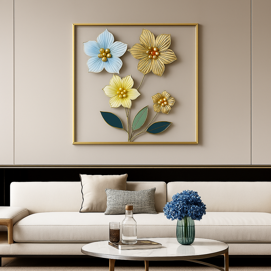 A square gold frame showcasing detailed metal flowers in soft blue, yellow, and gold hues, accented by elegant green and blue leaves.