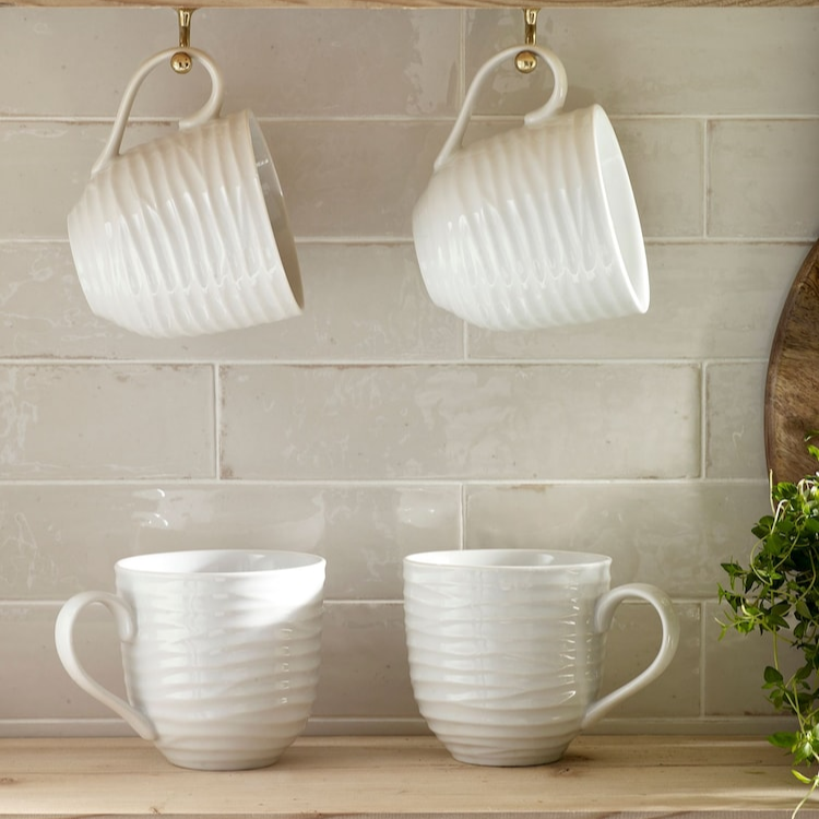 Porcelain mug with embossed design placed on natural wood coaster.