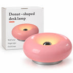 Pink donut-shaped LED table lamp lit on a bedside table, with touch control and three light tones