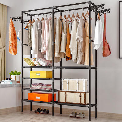 Freestanding metal clothes hanger with non-woven fabric shelves in a bedroom.