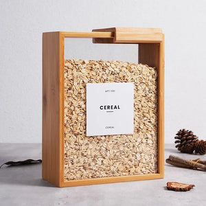 Modern bamboo and clear panel kitchen storage container holding cereal, rice, and protein powder, shown in a bright kitchen setting.


