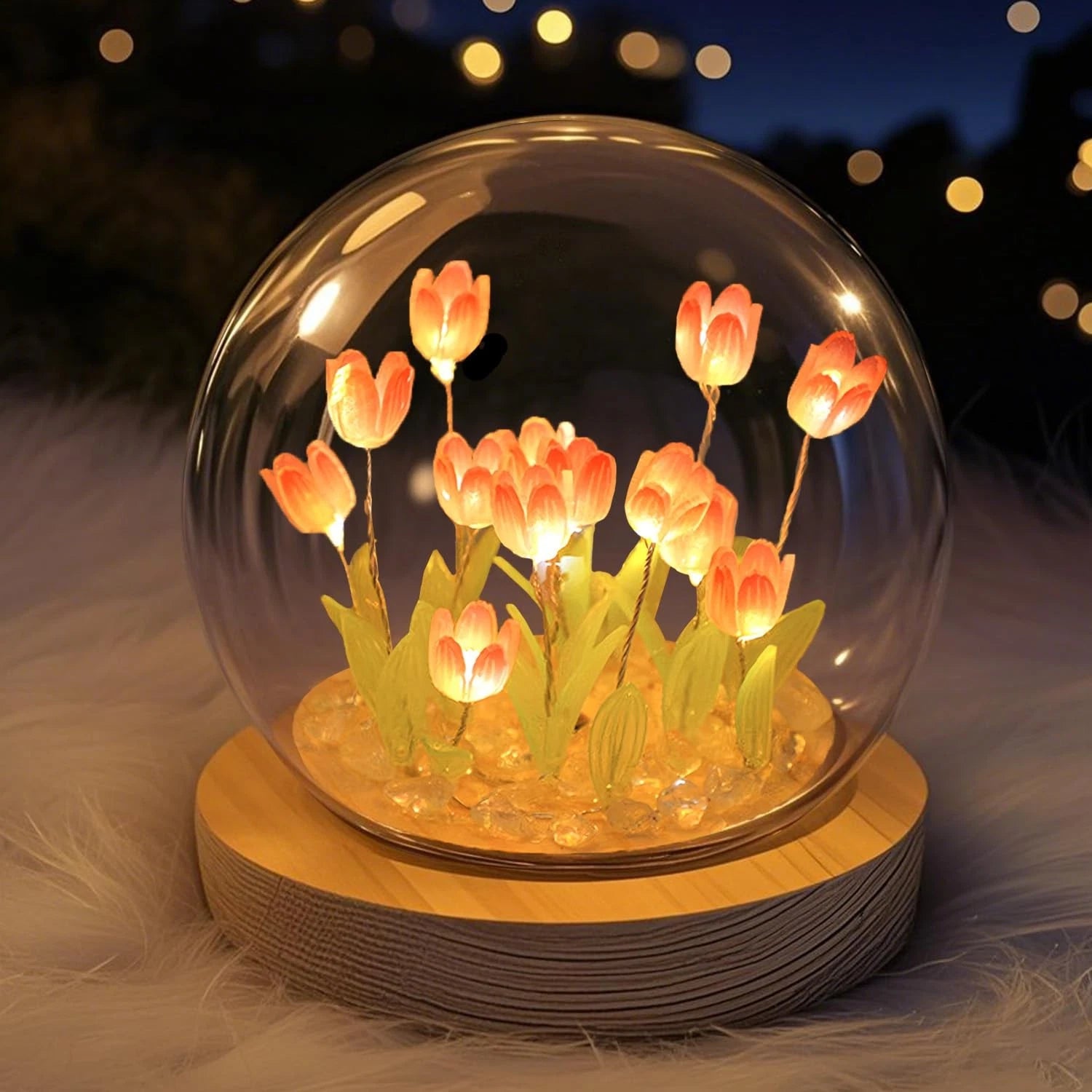Glass dome with illuminated tulips on a wooden base against a blurred background