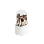 Set of makeup brushes in a white holder with a clear dome on a white background